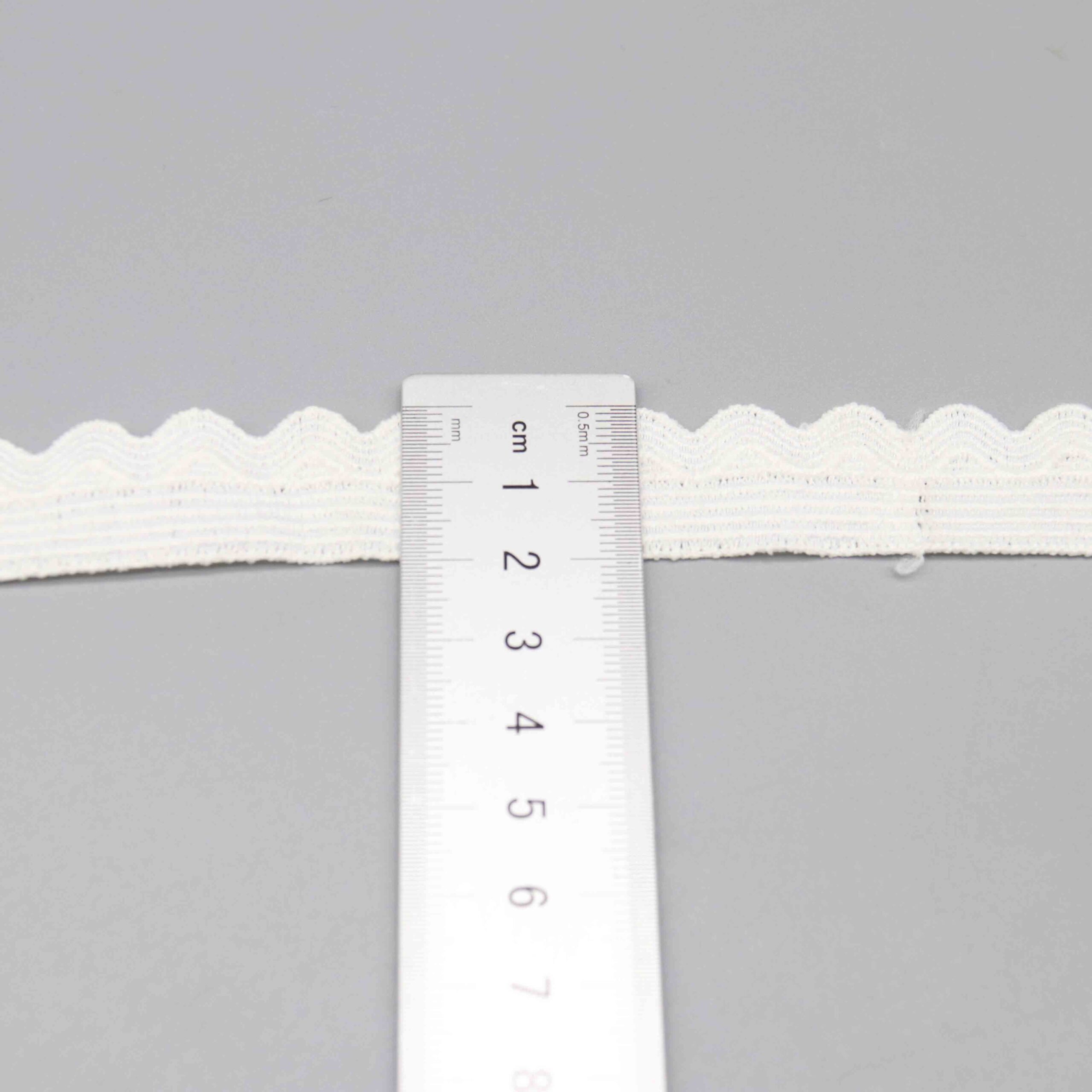 Close-up of a 2cm wide water-soluble polyester lace trim in pristine white, featuring a delicate scalloped wave design with smooth, clear contours for a simple yet elegant look; soft and fine texture ideal for garment edging, sewing details, and creative craft projects.