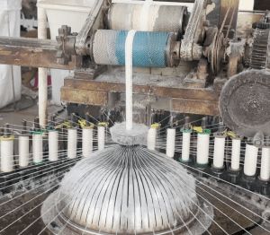 Wide view of a cotton thread lace manufacturing facility with skilled workers and advanced equipment handling large-scale lace production.