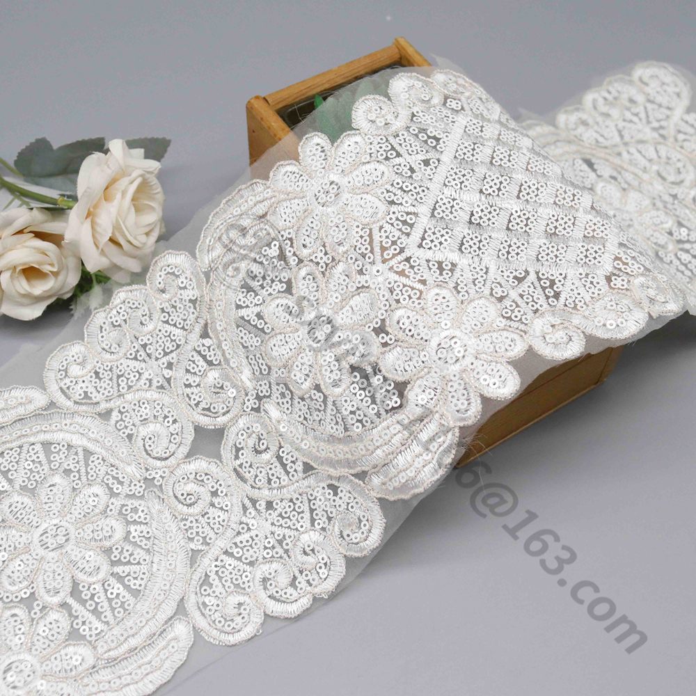 Detail of luxurious white lace trim, measuring 14cm wide and embellished with sparkling beads and sequins, designed for elegant bridal gown edging.