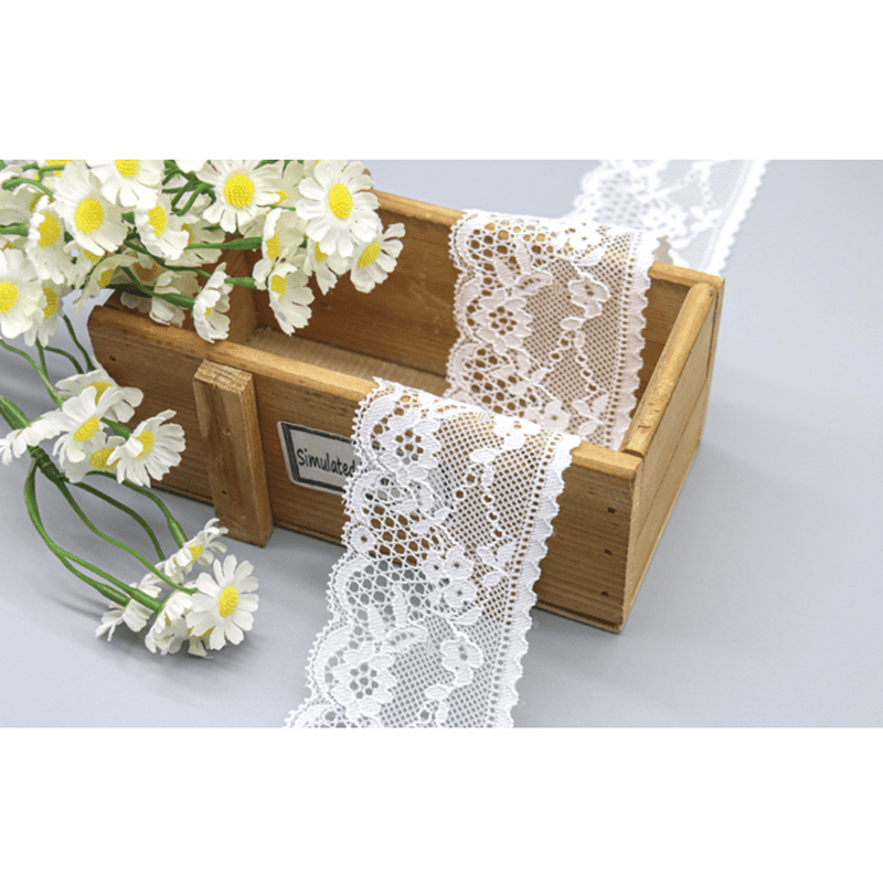 Detailed view of exquisite white lace trim with airy mesh openwork, prominent floral-vine designs in clear layers, and smooth wave-shaped borders enhanced by lockstitching; lightweight and elegant, perfect for bridal dress embellishments.