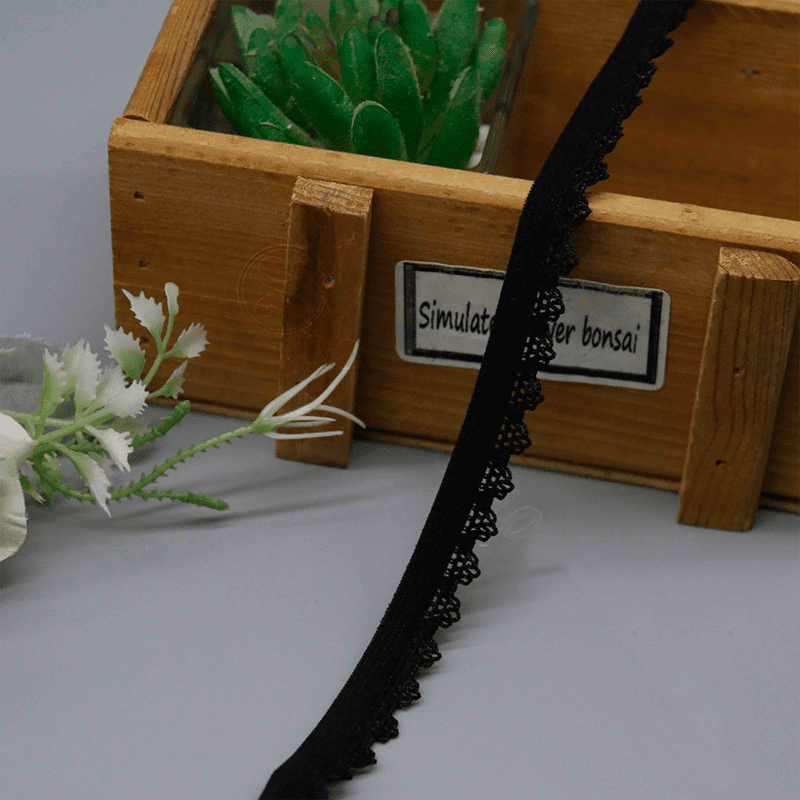 Artistic close-up of 1.1 cm black elastic lace trim with elegant, straightforward lines and detailed lace edging in a soft wave motif; breathable elasticity provides a comfortable experience, ideal for bulk sewing in garments, underwear, and personalized DIY projects.
