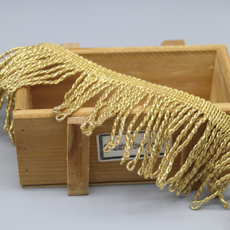 Top-down view of metallic gold fringe trim showing uniform strand length and wave pattern