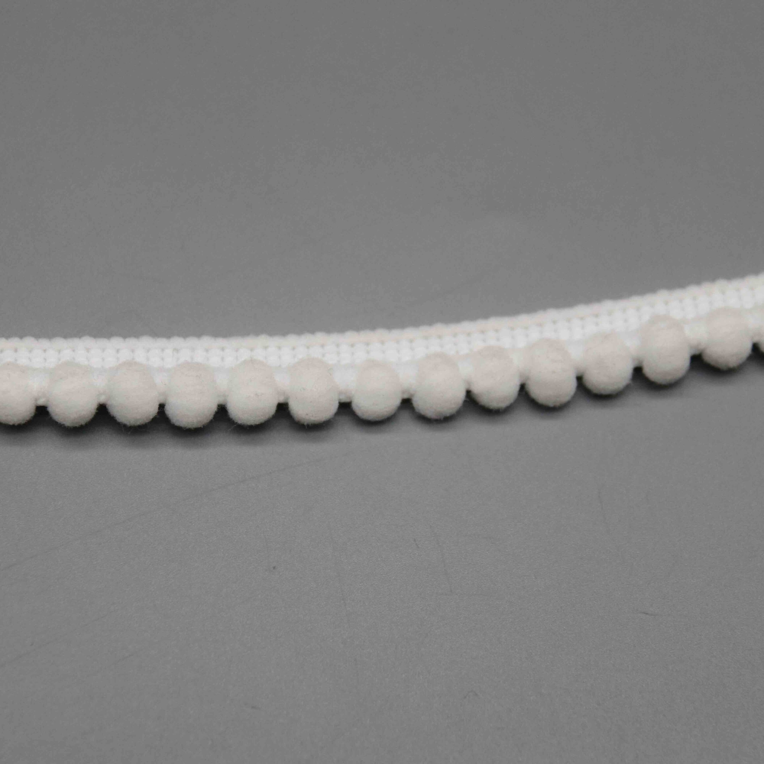 Macro close-up of the compact velvety pompom spheres and tight spacing on the nylon trim.