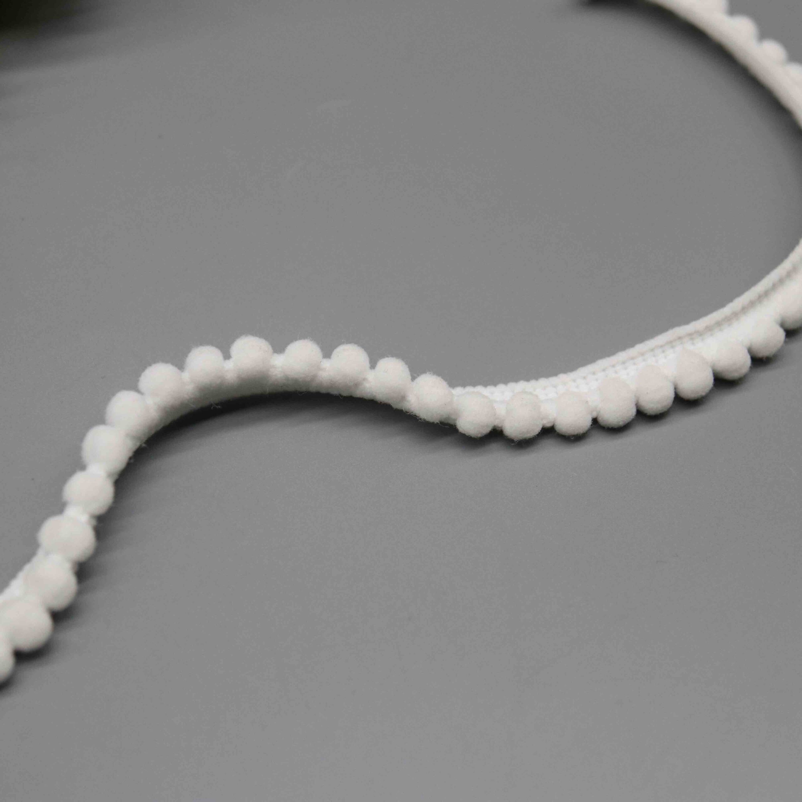 Angled shot capturing the soft matte nylon texture and fuzzy surface of miniature pompoms.