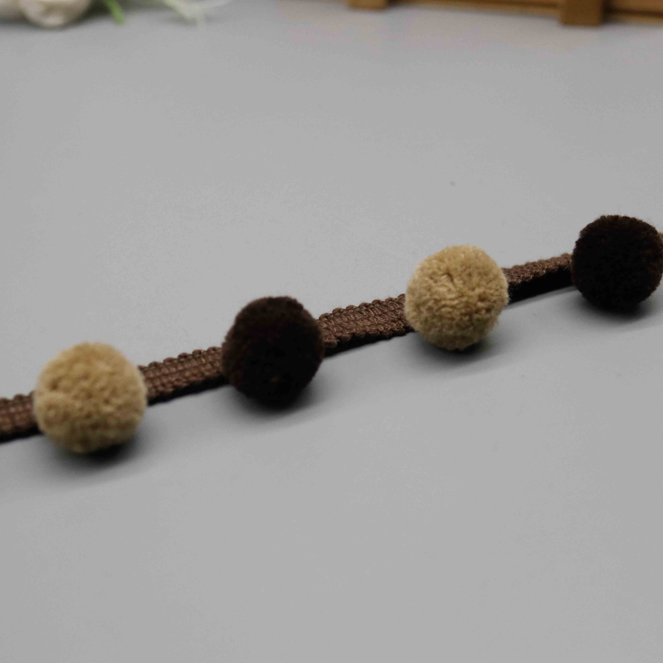 Angled shot capturing the dense velvety nylon texture contrast between dark and light pompoms.