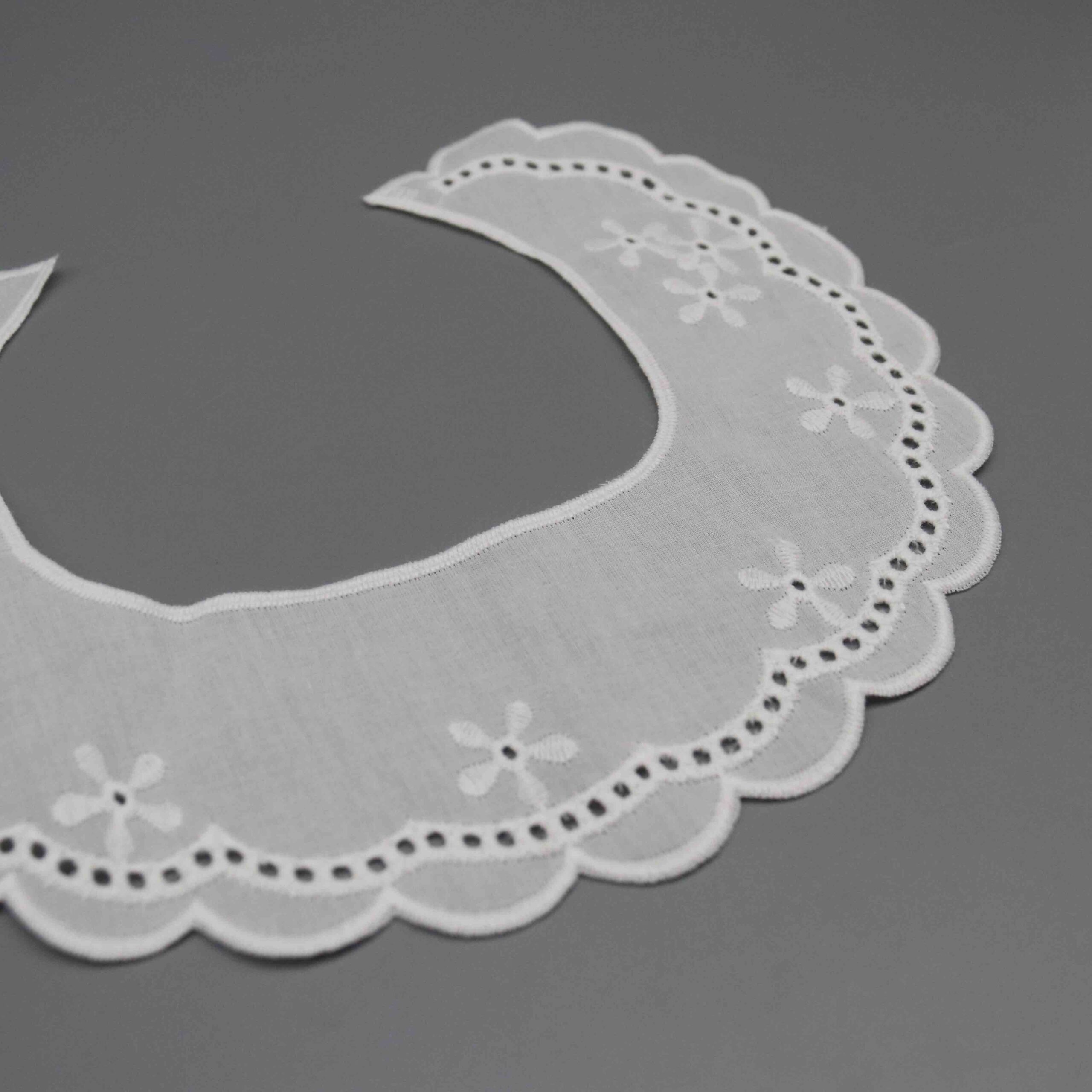 Macro close-up capturing delicate daisy motifs and precise thread craftsmanship on sheer cotton.