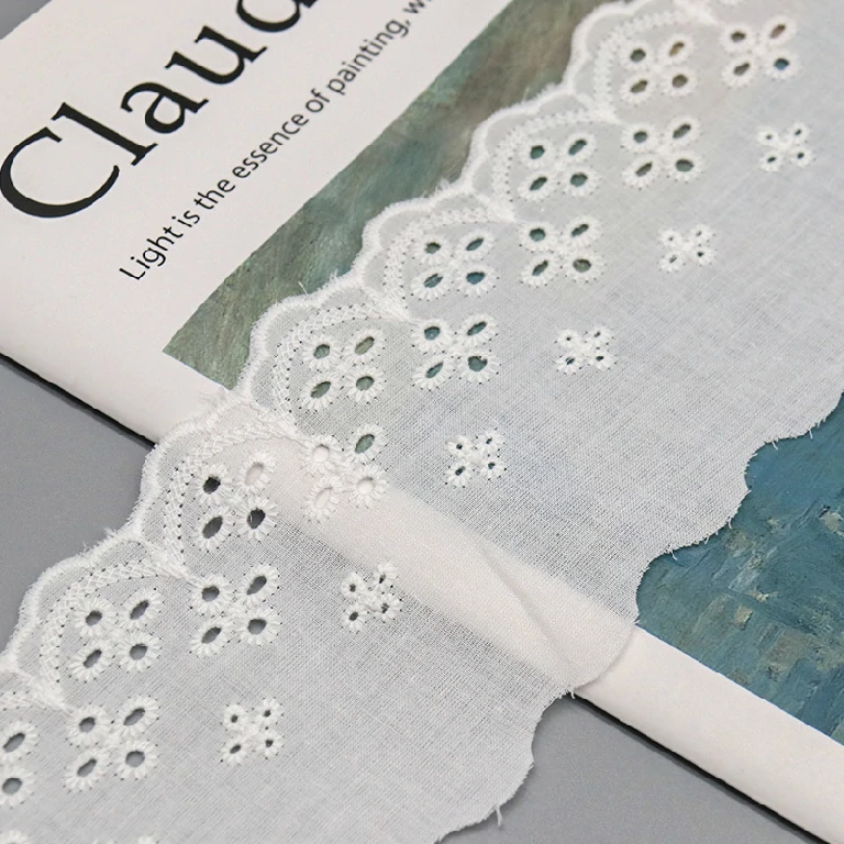 White cotton embroidered lace trim featuring floral patterns, ideal for sewing and garment decoration.