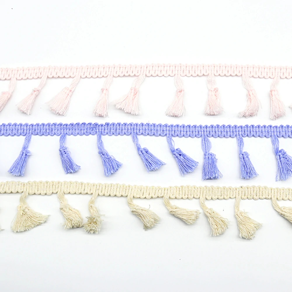 Macro shot of broom tassel knot details and braided header band on sage green polyester fringe trim.